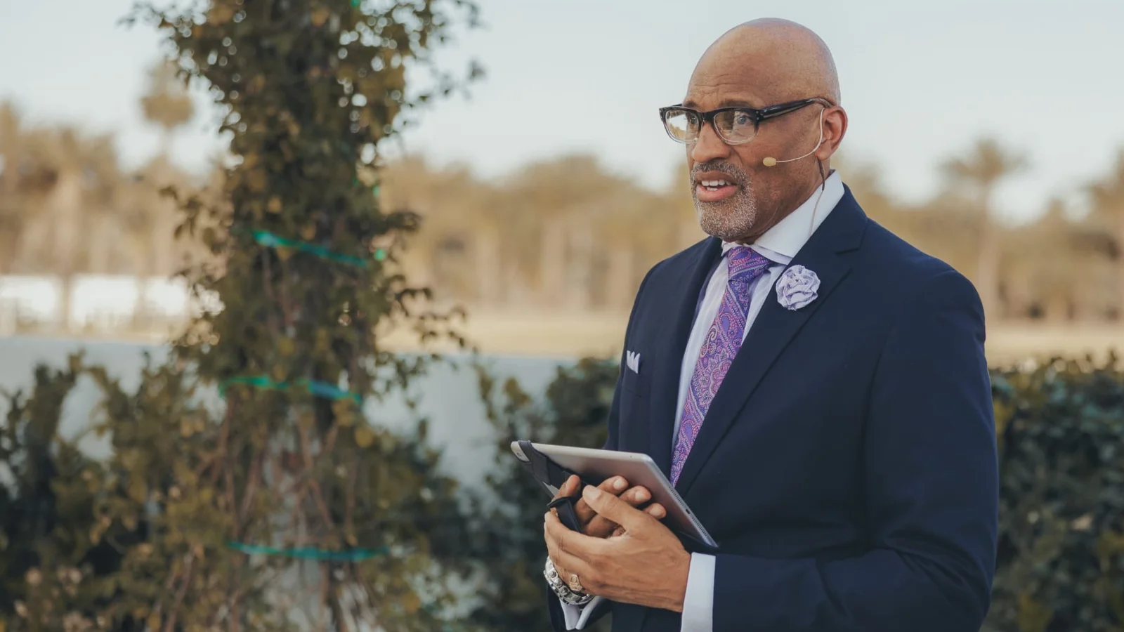 Dr. Nos speaking outdoors with a headset microphone